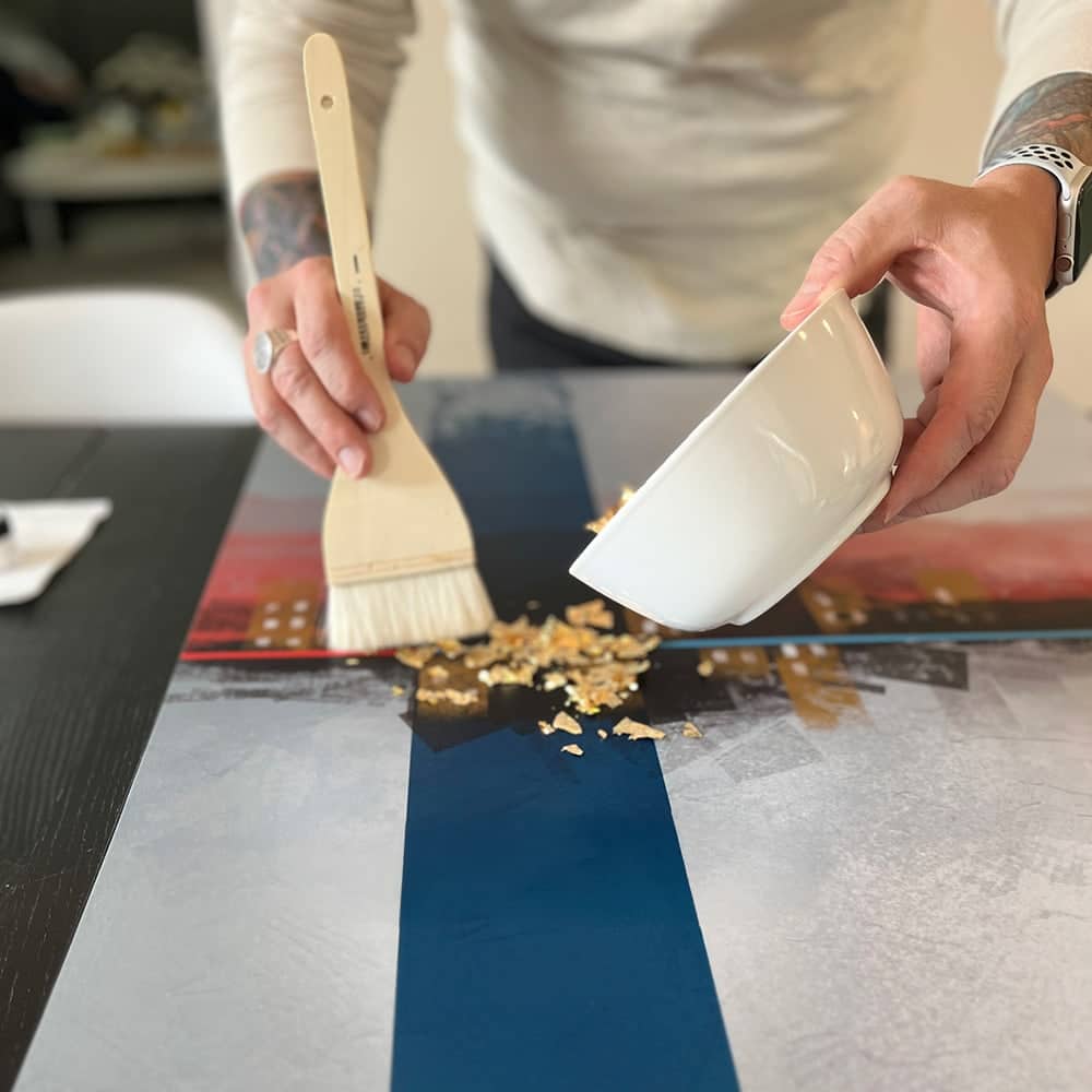 Applying gold leaf to painting